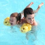 Dos niños bañándose en una piscina