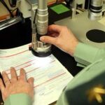 Un Guardia Civil trabaja con un microscopio para comparar tipos de letra
