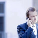 El consejero de Empleo, Manuel Recio, habla por un teléfono móvil en el Parlamento