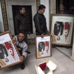 Varios operarios se llevan retratos del huído presidente tunecino, Zine el Abidine Ben Alí, que decoraban uno de los edificios de la sede del primer ministro, al sótano del edificio en Túnez (Túnez)