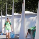 Dos jóvenes voluntarias preparan los confesionarios instalados en el parque a los que acudirán numerosos peregrinos