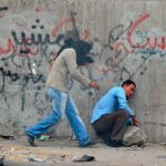 Un manifestante afectado por los gases lacrimógenos (d) recibe ayuda de otro durante los enfrentamientos con la policía y soldados en las proximidades de la Plaza Tahrir