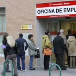 Un grupo de personas hacen cola en la entrada de una oficina de empleo