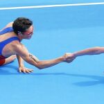 Alistair Brownlee, medalla de oro, da la mano a Gómez Noya, plata. Ambos están tumbados en el suelo tras el esfuerzo