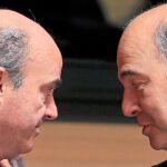 El ministro de Economía español, Luis de Guindos, conversa con su homólogo francés, Pierre Moscovici, durante la reunión en la que España se sumó finalmente a esta iniciativa