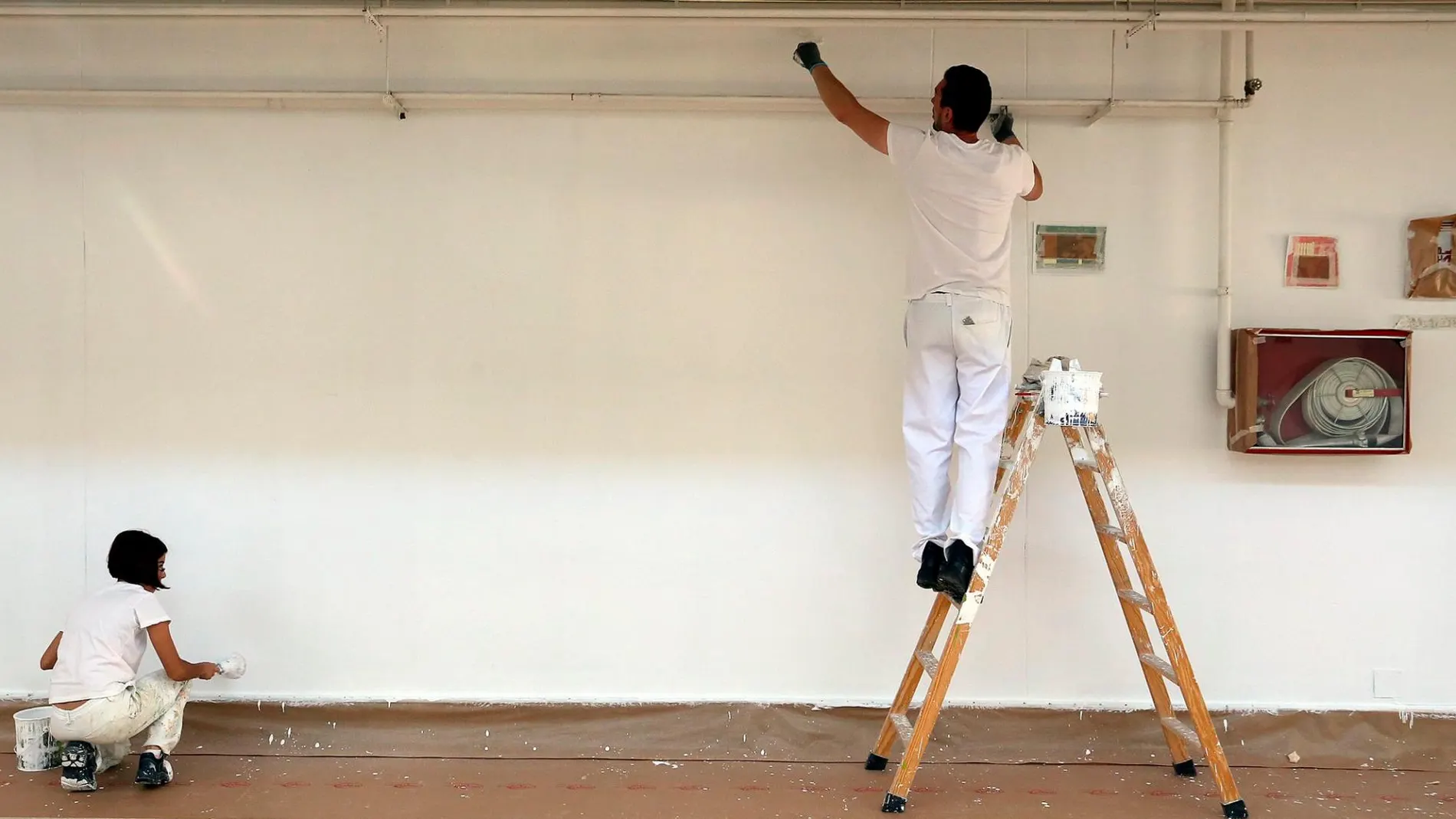 Un par de trabajadores pintando una pared