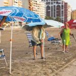 Imagen de archivo de varias personas mayores colocando las sombrillas a primera hora de la mañana