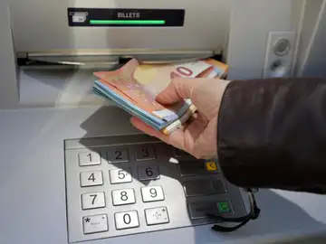 Una mujer saca dinero en un cajero automático Una mujer saca dinero en un cajero automático