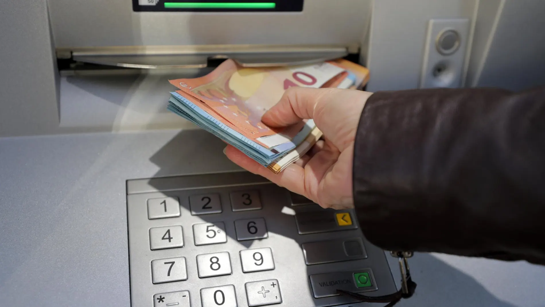 Una mujer saca dinero en un cajero automático