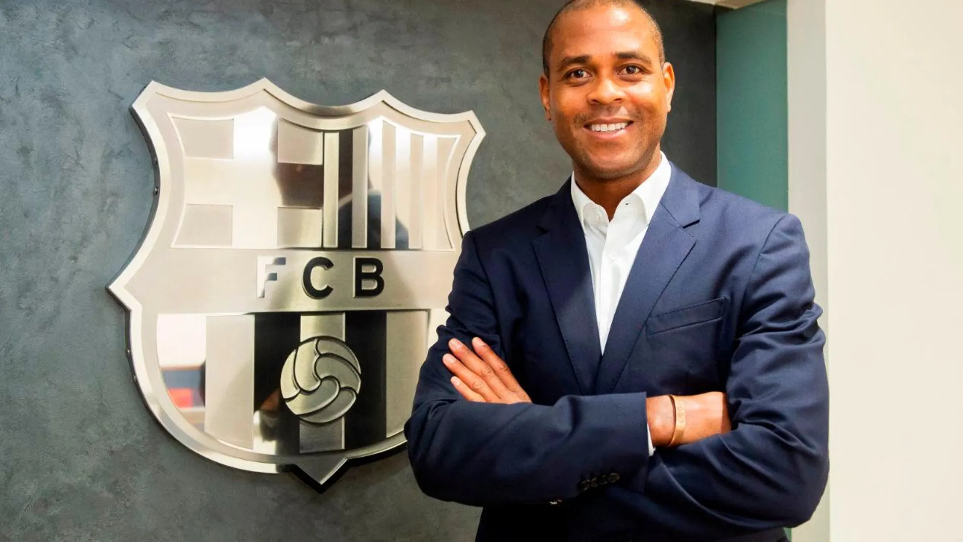 Patrick Kluivert posa, delante del escudo del FC Barcelona, como nuevo director de la cantera