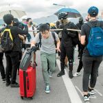 Un viajero trata ayer de esquivar a los manifestantes para acceder a la terminal de salidas del aeropuerto internacional de Hong Kong