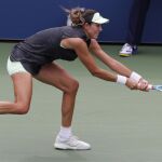 Garbiñe Muguruza trata de devolver con un revés a dos manos una pelota ante la estadounidense Riske