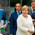 Jean-Claude Juncker, presidente del Ejecutivo comunitario, permanece sentado en presencia de Angela Merkel