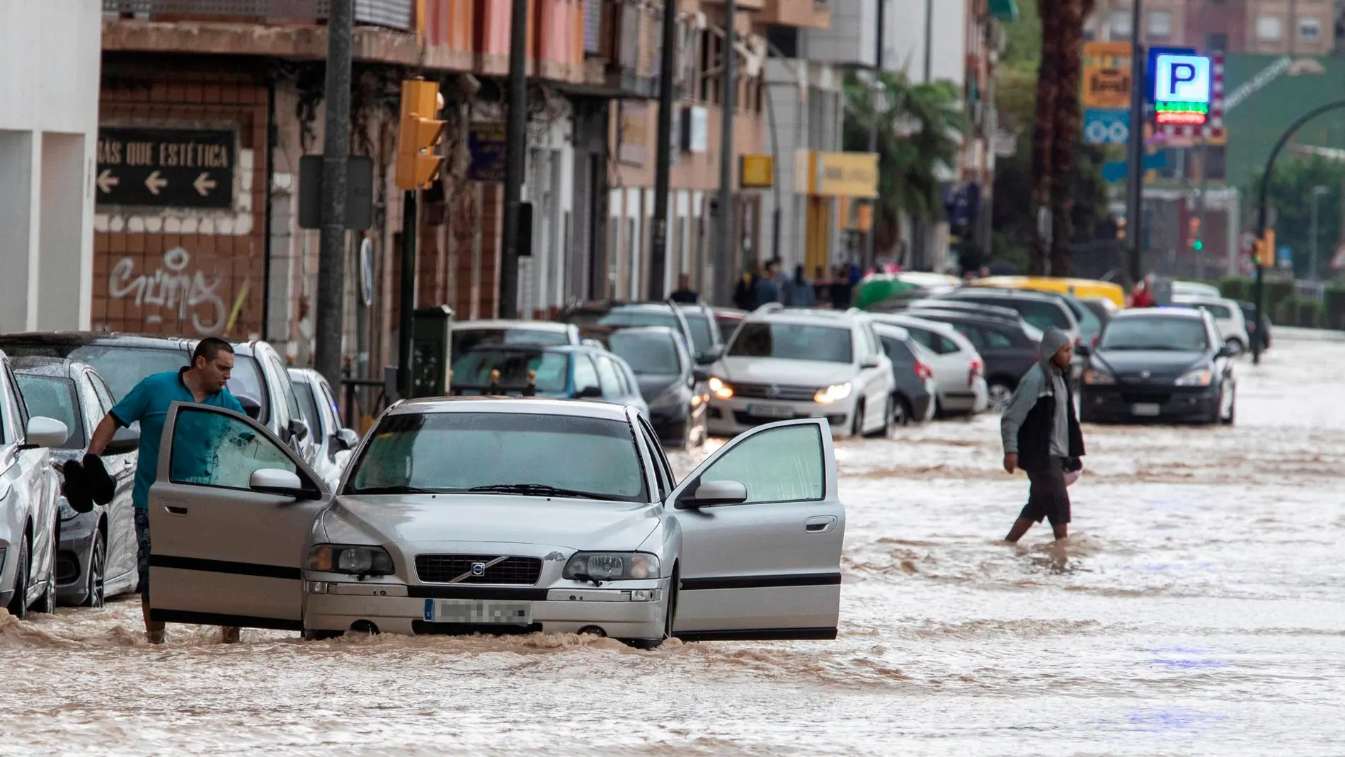 Voluntarios de protección civil trasladan a un hombre en silla de ruedas tras las intensas lluvias esta tarde en el barrio de Runes, Blanca