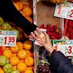 Una persona compra en una frutería de un mercado de Sevilla