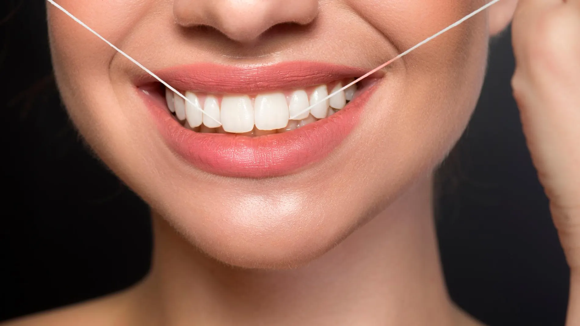 Una mujer utilizando hilo dental