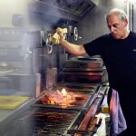 El cocinero Victor Arguinzoniz, junto a las brasas, mientras elabora uno de sus grandes platos ©ASADOR ETXEBARRI