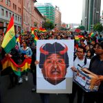 Manifestantes llevan una pancarta con el rostro de Evo Morales con cuernos rojos en una marcha de protesta en La Paz / Reuters