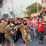 Manifestantes antigubernamentales ayudan a un miembro de las fuerzas de seguridad en una manfiestación en Bagdad/Ap