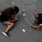 Dos niñas dibujan en la calle