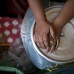 María de Coronel junto pone las manos en una cazuela en su restaurante en La Paz, que sufre la escasez de alimentos por las protestas