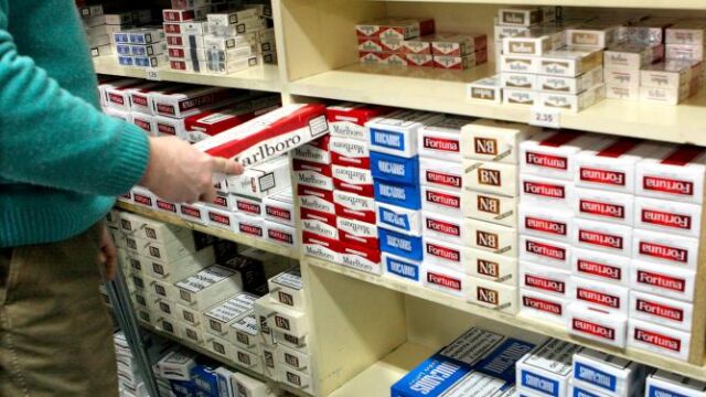Empleado de un estanco con un cartón de tabaco en la mano