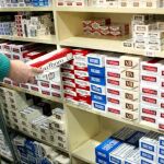 Empleado de un estanco con un cartón de tabaco en la mano