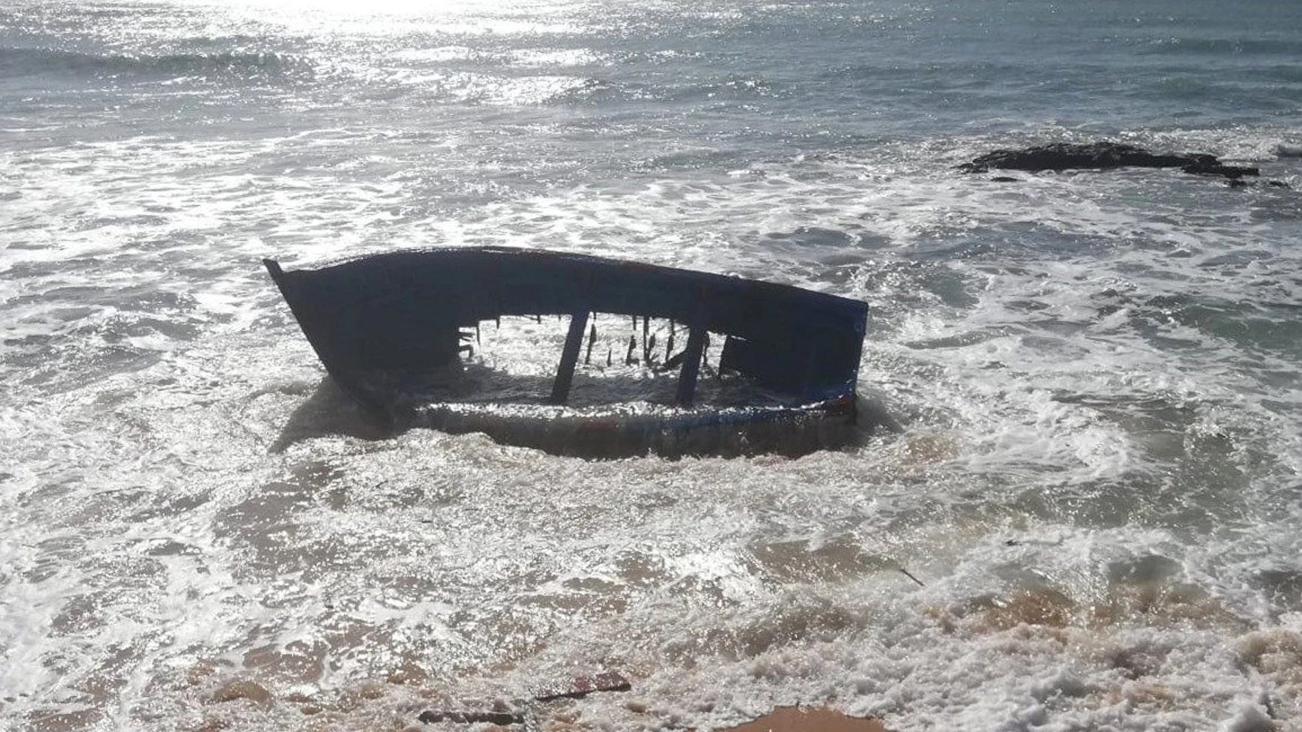 Fotografía facilitada por la Guardia Civil del estado en el que quedó una patera tras chocar contra una roca ayer en la playa de Caños de Meca (Cádiz). EFE