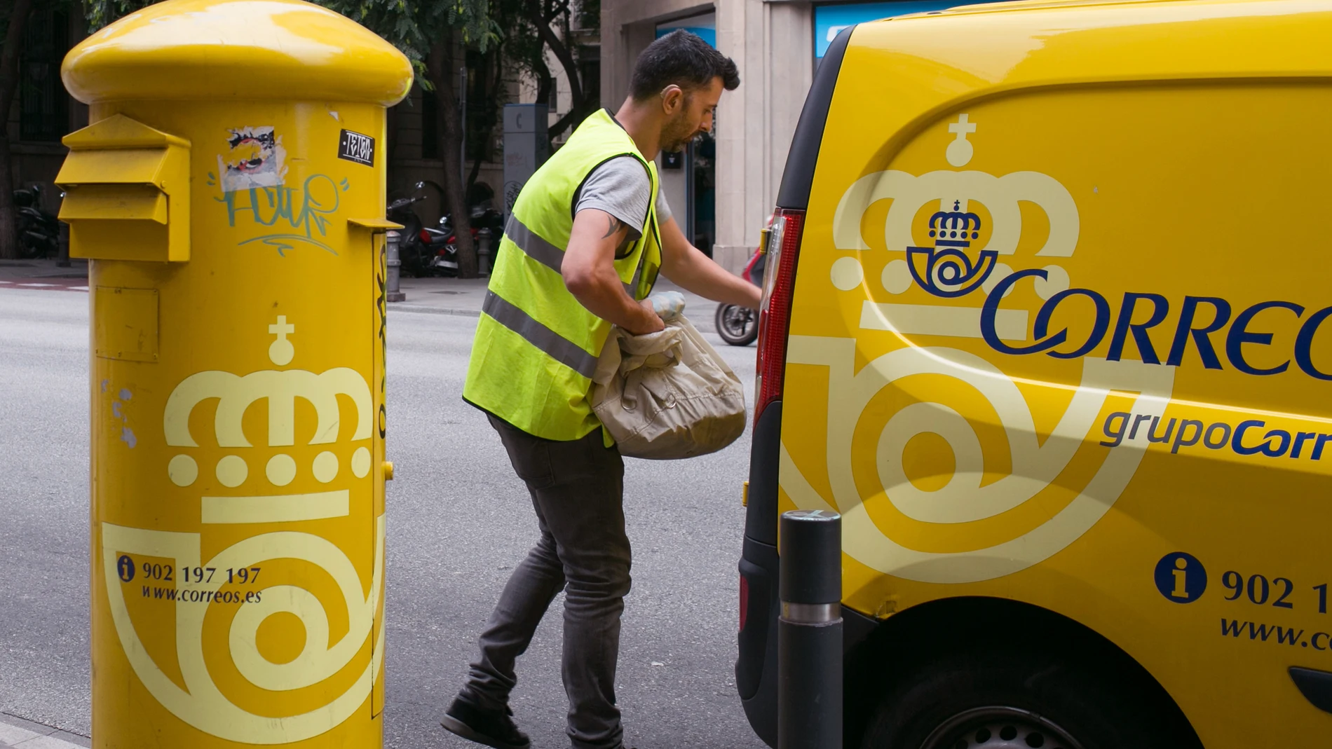 Un cartero recoge cartas de un buzón en las calles de Barcelona