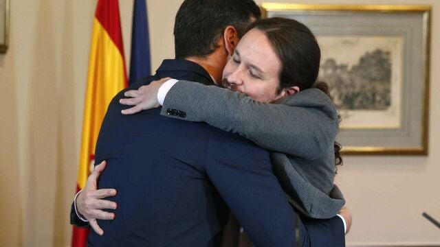 El presidente del Gobierno español en funciones, el socialista Pedro Sánchez (i), y el líder de Unidas Podemos, Pablo Iglesias, se abrazan en el Congreso tras firmar un acuerdo para la formación de un Ejecutivo, el 12 de noviembre