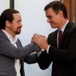 GRAF5366. MADRID, 30/12/2019.- El candidato a la investidura, Pedro Sánchez (d), y el líder de Podemos, Pablo Iglesias (i), estrechan sus manos tras el acto de firma del acuerdo programático con las principales medidas que tomará el futuro Gobierno de coalición. En el salón Chimenea de la Cámara Baja con las banderas de España y la UE detrás y sin más decorado que la mesa para la firma y un atril, Sánchez e Iglesias han firmado su acuerdo de Gobierno en presencia de sus respectivos equipos negociadores y cargos del Gobierno en funciones, PSOE y Podemos. EFE/JuanJo Martín
