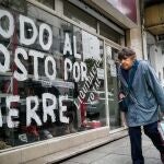 Una mujer pasa frente a una vitrina que anuncia su liquidación por cierre