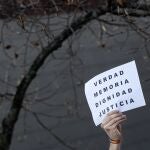 Una persona reivindica con un cartel "verdad, memoria, dignidad y justicia" frente al monumento a las víctimas del terrorismo levantado en la plaza del Baluarte de Pamplona