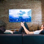 Un hombre viendo la televisión en el salón de su casa
