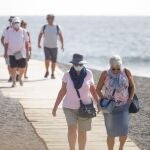 Varios turistas pasean por las inmediaciones del hotel de Tenerife en el que desde el pasado lunes permanecen incomunicados sus huéspedes y trabajadores por el coronavirus