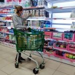 na cliente con mascarilla observa estantes vacíos de jabón de manos en un supermercado de Madrid