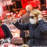 Una mujer en el Mercado Central de Valencia se protege con mascarilla del contagio por coronavirus