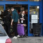 Un policía trata de mediar entre varias personas agolpadas a la entrada de un supermercado en el barrio madrileño Vallecas, este sábado. Agentes de la Policía Nacional han acudido este sábado a un supermercado del distrito madrileño de Villa de Vallecas ante la actitud violenta de varios clientes que golpeaban las lunas para apremiar a los empleados del establecimiento a abrir. EFE/Víctor Lerena