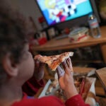 Un niño come un trozo de pizza