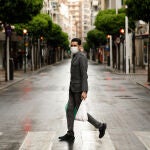 Una persona con mascarilla recorre las calles de Murcia, vacías durante el estado de alarma, con bolsas de plástico en las manos, en Murcia (España) a 22 de marzo de 2020.22-03-20 CALLES VACIAS EN MURCIA POR EL CORONAVIRUS COVID 19 CALLE ALEJANDRO SEIQUEREdu Botella / Europa Press22/03/2020
