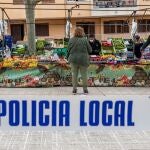 Miembros de la Policia Local y Voluntarios de Protección Civil se encargan de que se cumplan las medidas de seguridad durante el mercado semanal de Andraxt, en Mallorca, este miércoles, repartiendo guantes a los compradores y ocupándose de que respete un metro de distancia entre compradores y vendedores.