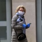 Una mujer se protege con guantes y mascarilla para salir a la calle en Sevilla
