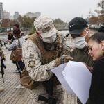 Un soldado revisa el salvoconducto de una mujer para acceder a una zona sometida a curantena en Santiago de Chile/AP