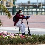 Una trabajadora de desplaza en un patinete protegida con una mascarilla por una calle de Málaga. EFE/Daniel Pérez