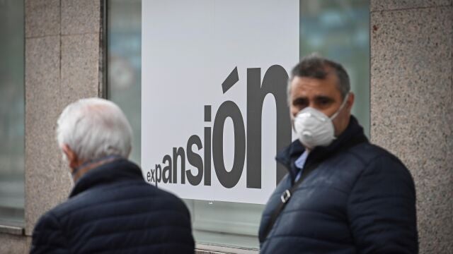 Un hombre con una mascarilla junto a una sucursal bancaria en Alcalá de Henares el pasado miércoles