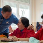 Un voluntario de La Caixa atiende a dos personas con diversidad funcional en una actividad solidaria