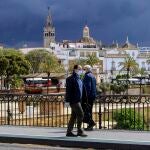 Dos hombres con mascarillas cruzando el puente de Triana, en Sevilla