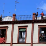 Un grupo de personas se asoman a los balcones y la azotea de sus viviendas durante el confinamiento en Sevilla