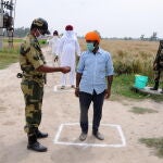 Un soldado pide la identificación a los granjeros cerca de la frontera con Pakistán