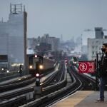 A man wearing a face mask waits for a subway at a quiet Fordham Road station in the Bronx, Friday, April 17, 2020, in New York during the coronavirus pandemic. Hopeful talk about getting people out of their homes and back to work in some parts of the country seems a far cry from the harsh reality in New York and its suburbs: Thousands of people infected with the coronavirus are still streaming into hospitals every day. (AP Photo/Mark Lennihan)